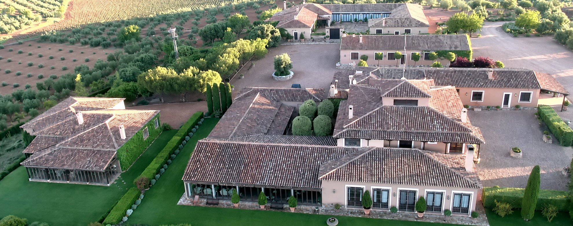 Aerial view of the lodge complex at El Crespo, tiled roofs and gravel courtyards among olive groves