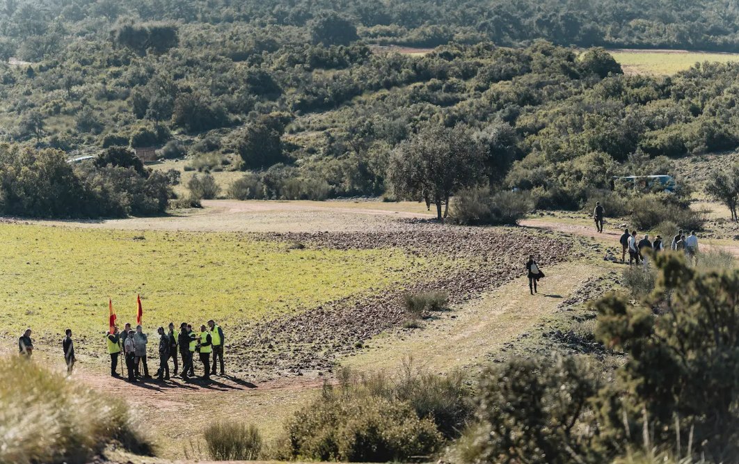 Beaters with flags gathered on a track in a broad valley of scrub and stubble at El Despenadero
