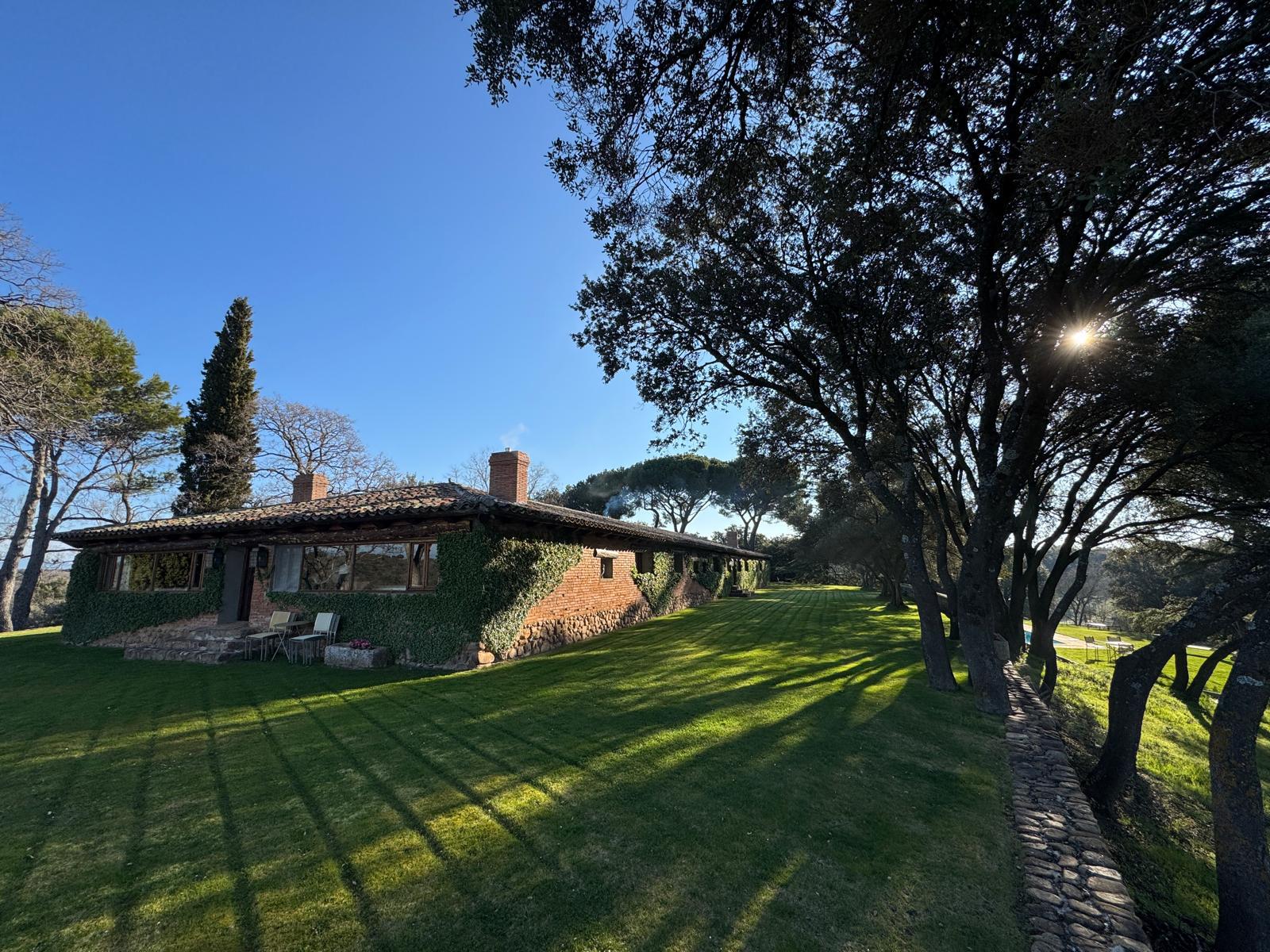 The ivy-clad lodge at Fuentelfresno under a pantiled roof, with mown lawn and mature trees
