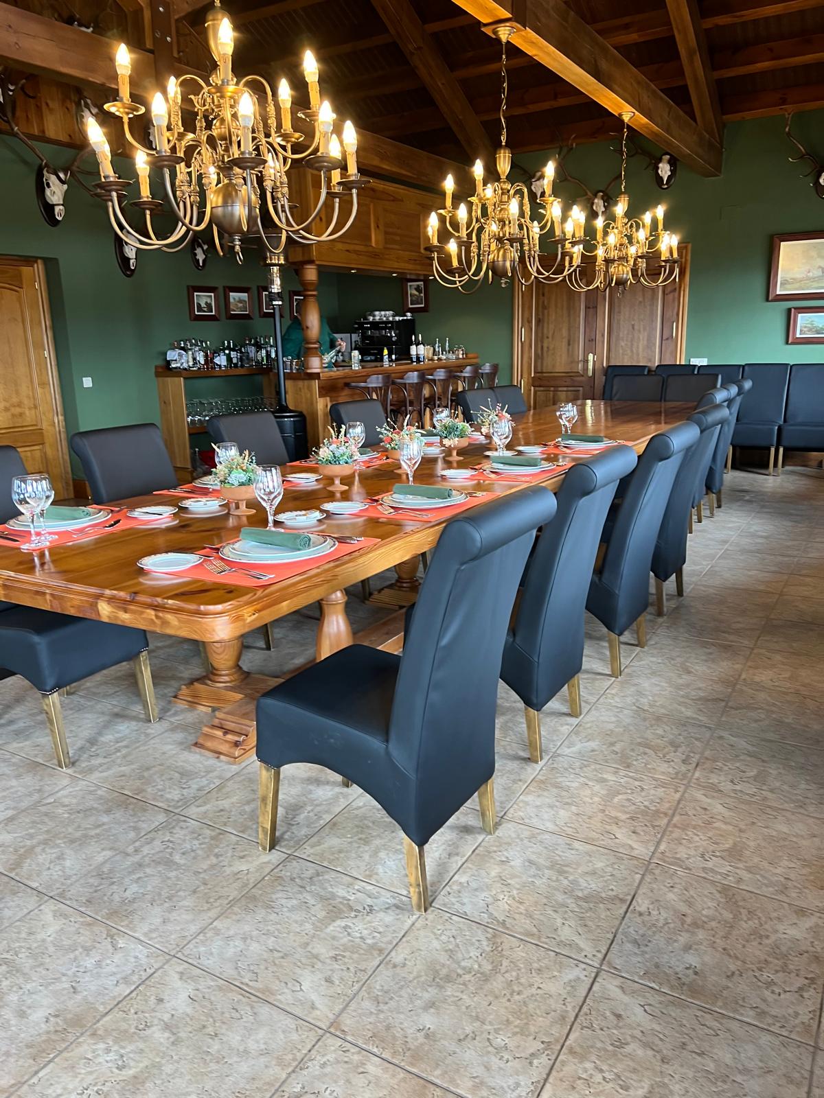 Long dining table laid for a shoot party beneath brass chandeliers at La Cuesta