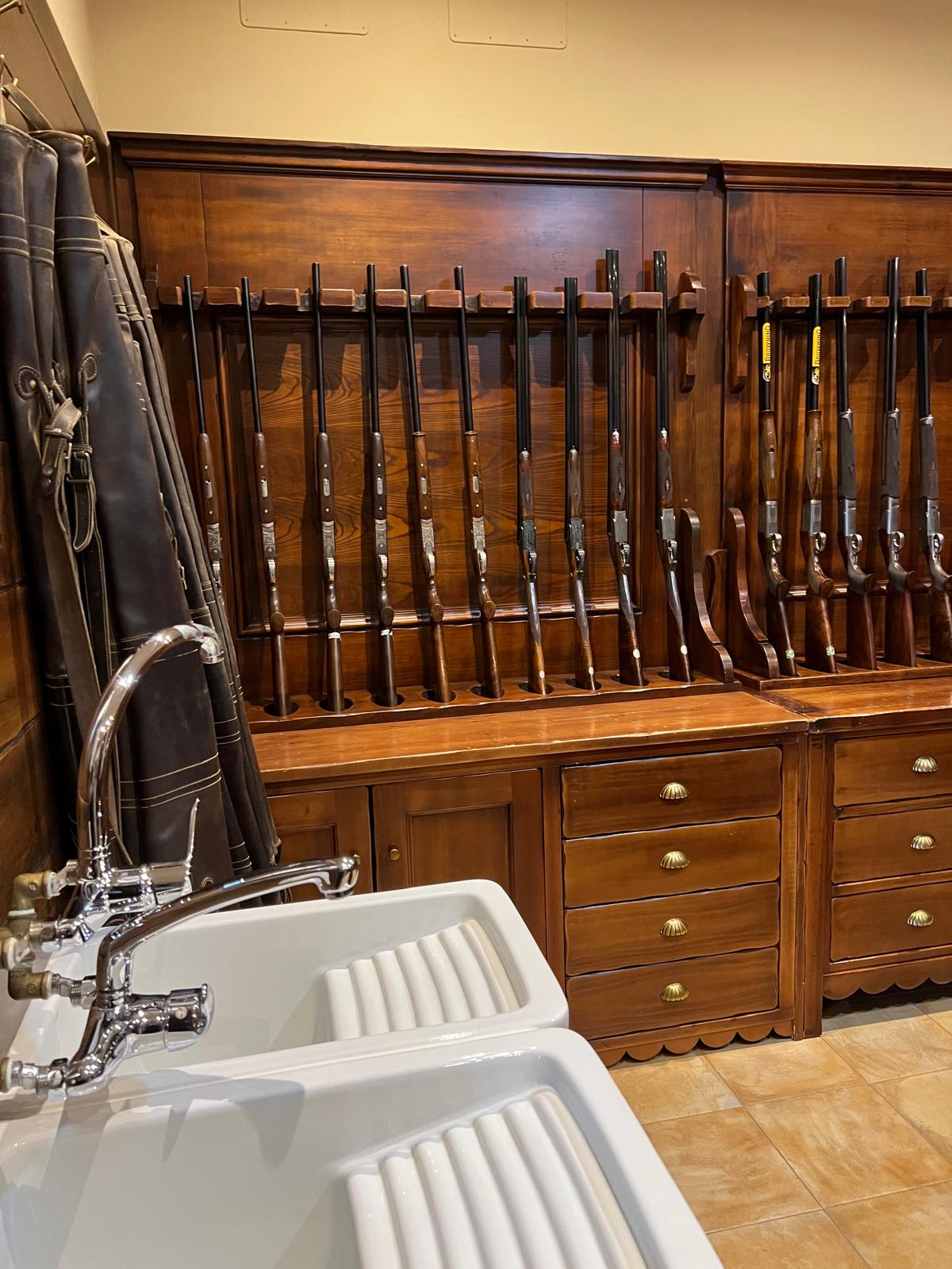 The La Cuesta gun room with racked shotguns, leather gun slips and twin cleaning sinks