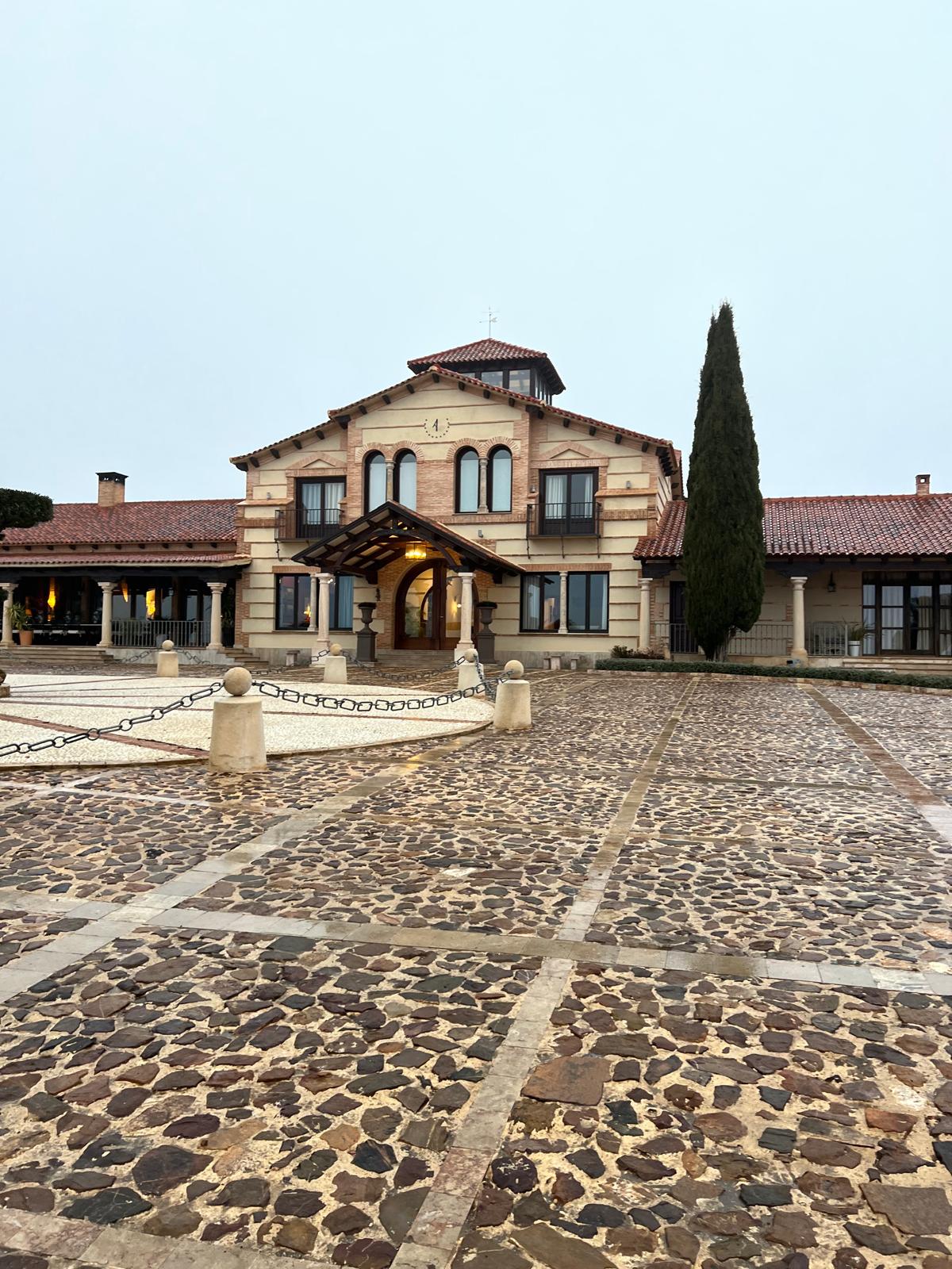 Stone facade and arched entrance porch of the La Cuesta lodge across the cobbled forecourt