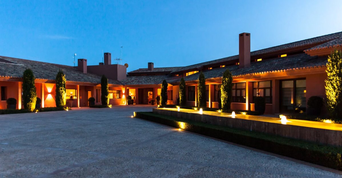 The courtyard at La Nava at dusk, warm uplighting along the colonnade