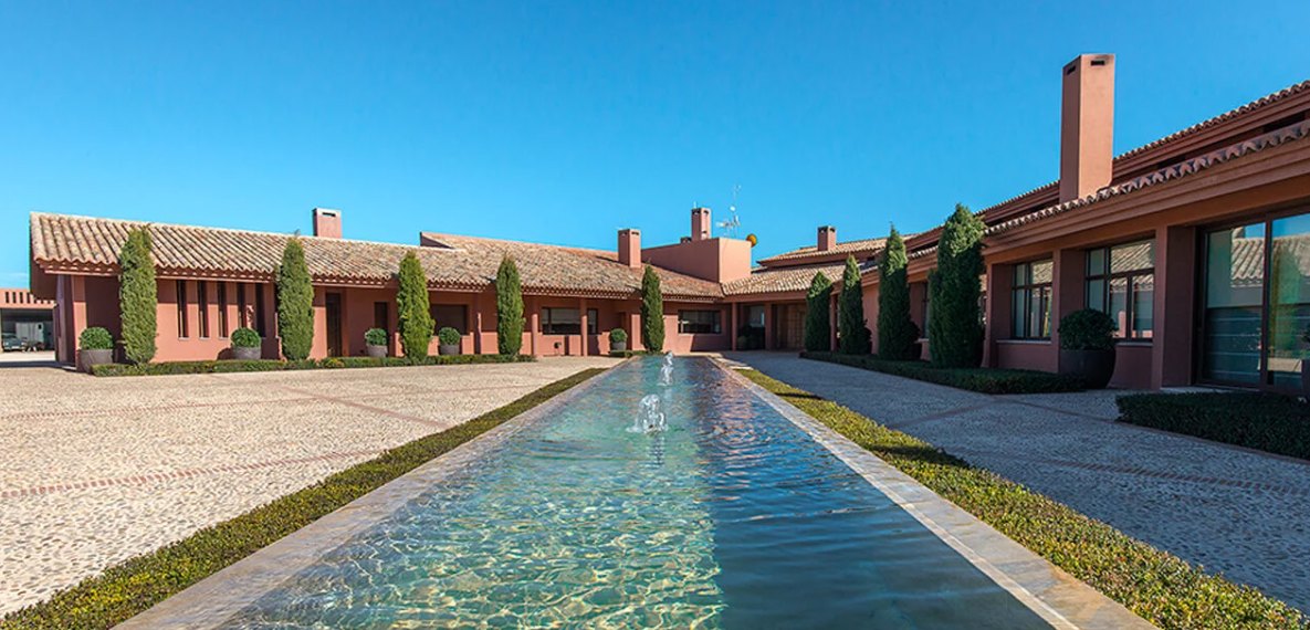 A long reflecting pool running between cypress trees in the courtyard at La Nava