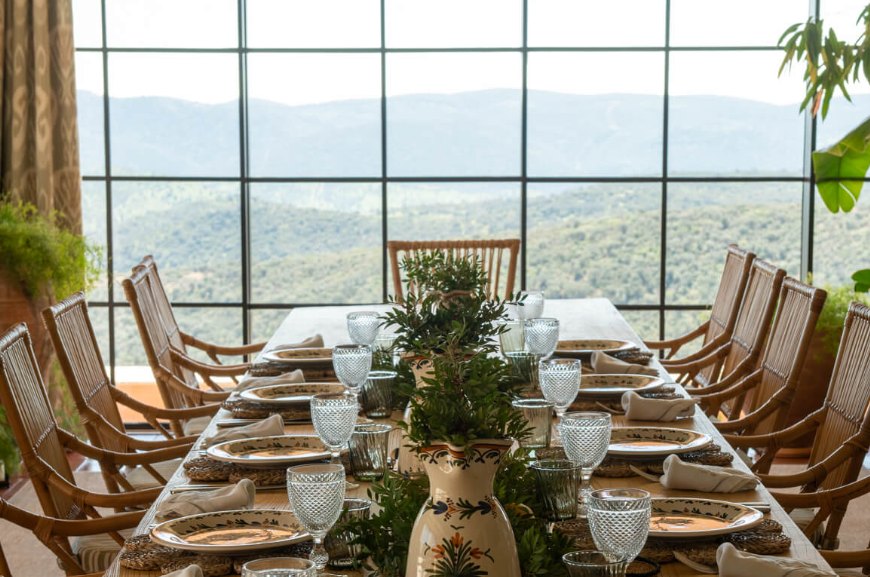 The dining room at La Nava laid for twelve, before a window looking over wooded hills