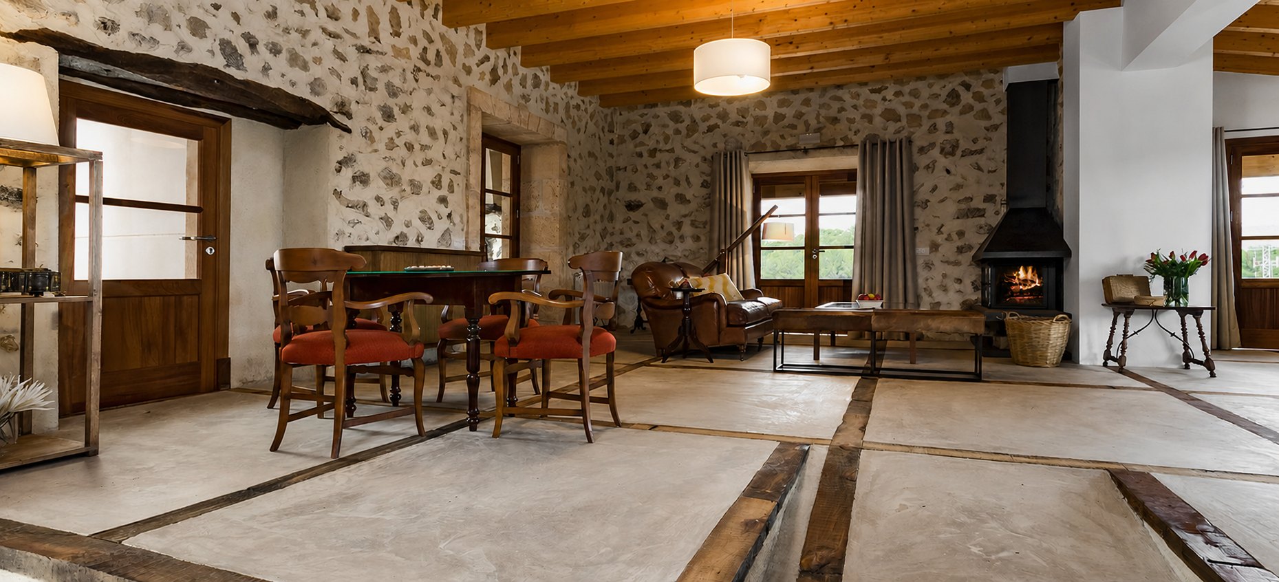 The living room at Las Barracas, rough stone walls and a timber-beamed ceiling above a lit wood fire