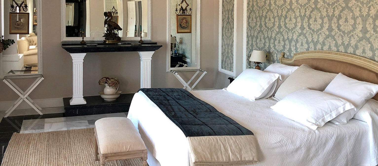 A bedroom at Ventosilla with damask wallpaper, a carved gilt headboard and a marble floor